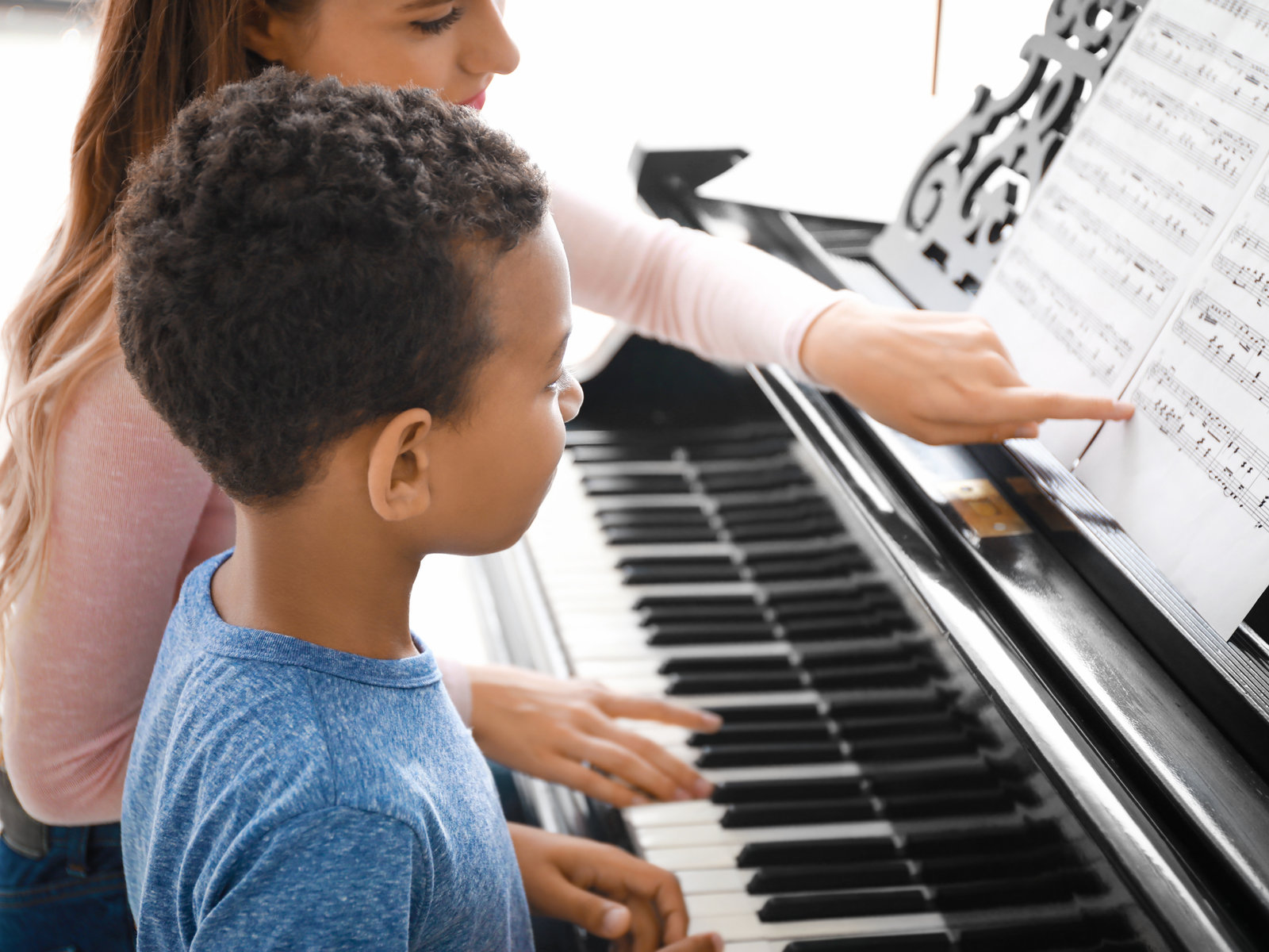 A teacher guiding a young pianist